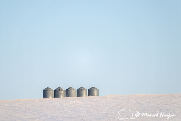 Sunrise over grain silos and snowy wheatfields, Alberta, Canada