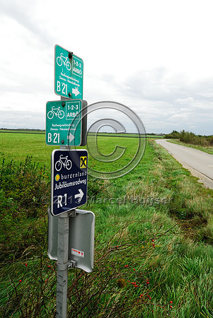 Bicycle route signs near multifunctional overpass (wildlife, bicyclists, pedestrians; about 100 m wide), across A4 motorway, Parndorf, Austria