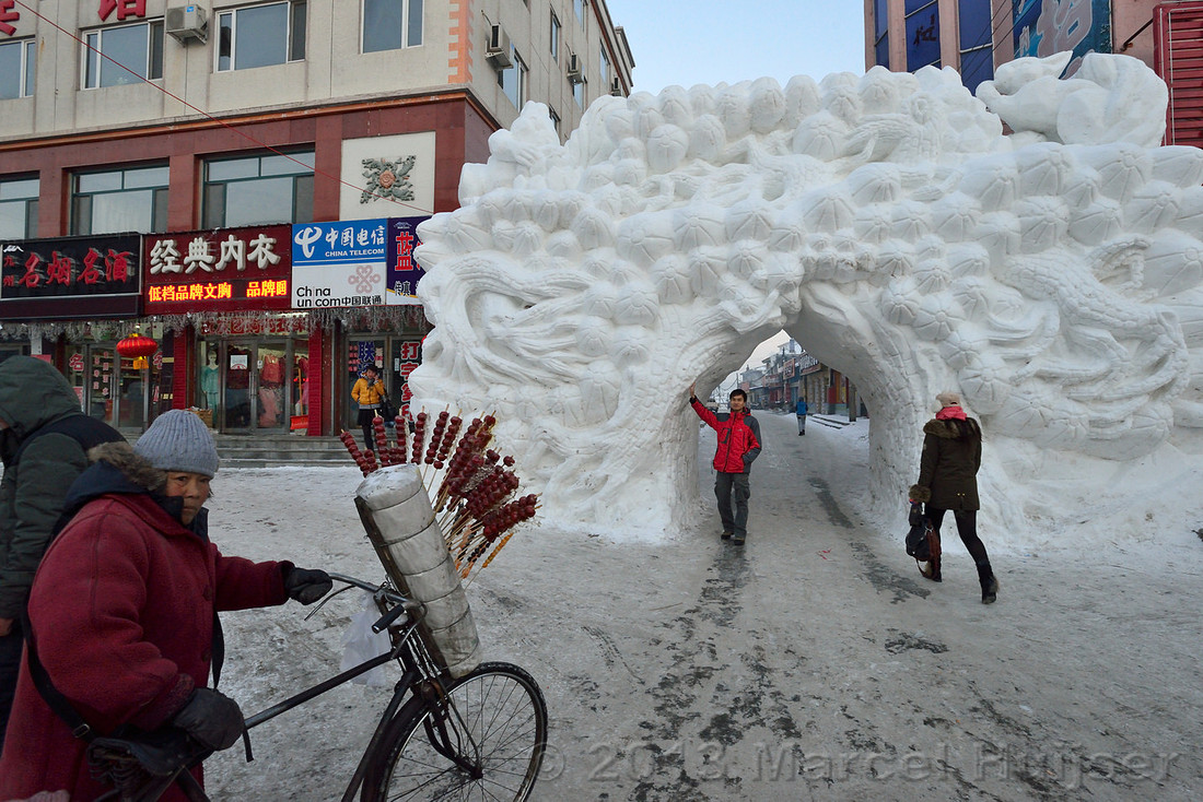 Street vendor with snow sculpture in the background, Erdaobaihe. Jilin Province, China