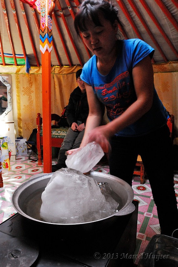 Sola melts ice from the river on wood stove, at Nara