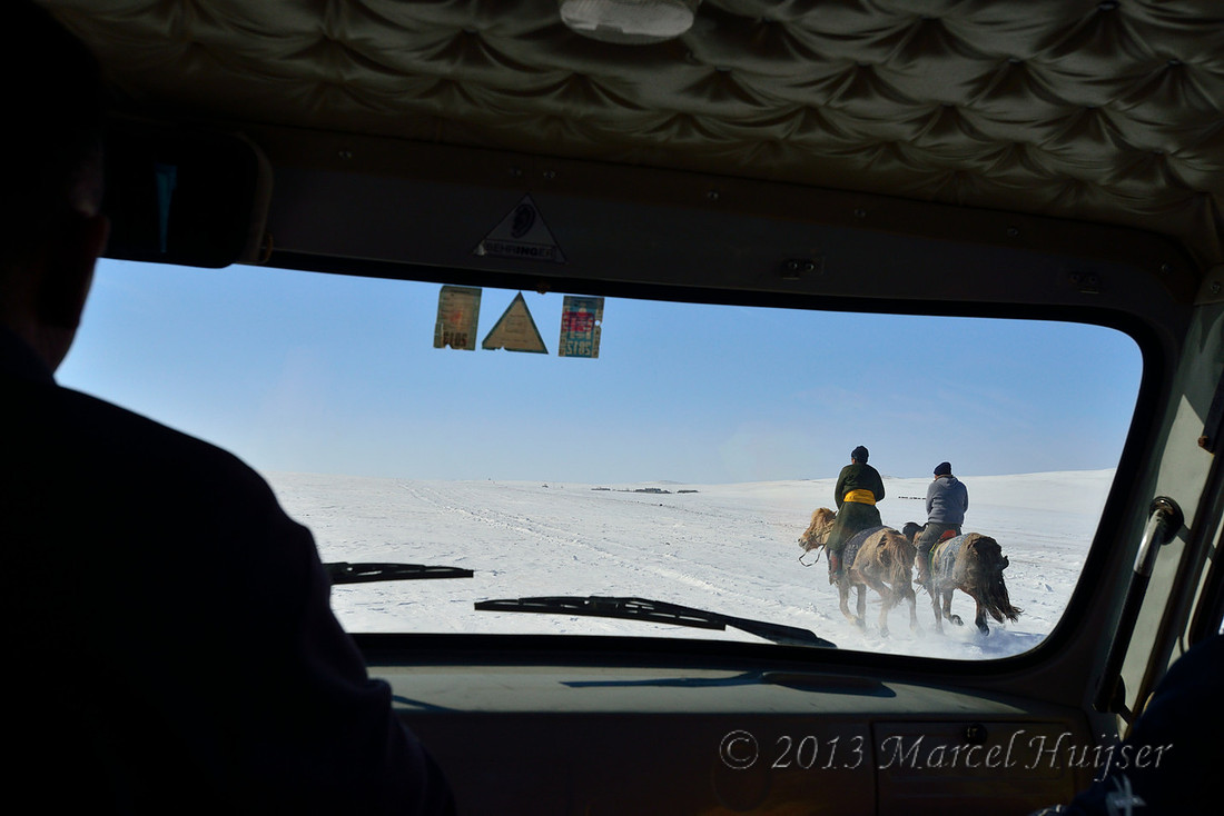 Travel: We pass two people on horses on snow covered grasslands, near Bayan-Adarga, Khentii, Mongolia.