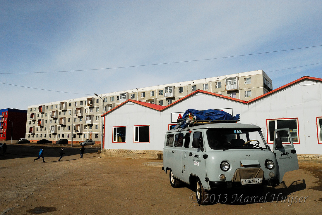 Travel: Our van in front of a store and apartment blocks, Choyr, Govisümber, Mongolia