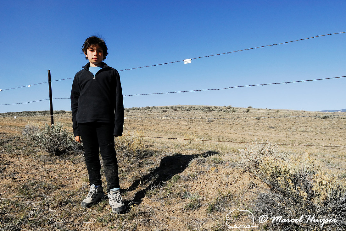Emiliano Ferguson in front of livestock fence with markers for sage grouse