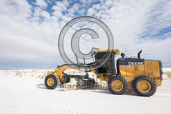 Grader clearing the road of sand (gypsum) in the morning, White