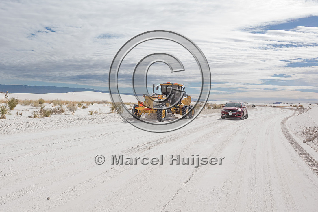 Grader clearing the road of sand (gypsum) in the morning, White