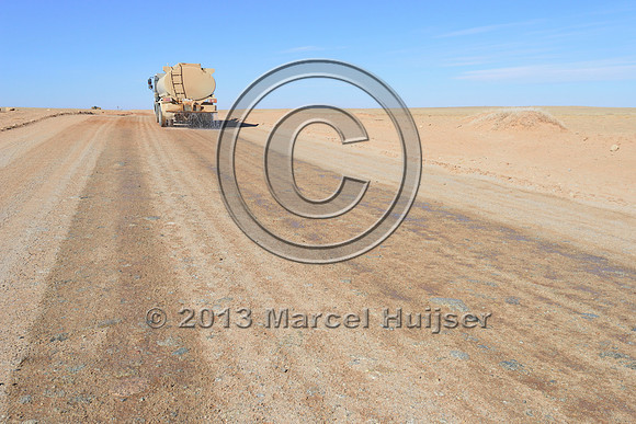 Water truck sprays water on road for dust control, Gobi, Mongolia