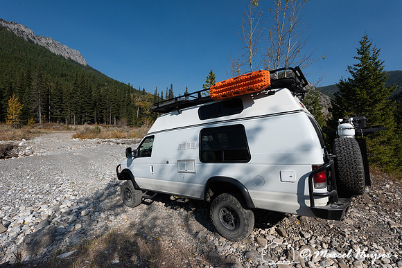 Camper van crossing dry creek, Rocky Mountains, Montana