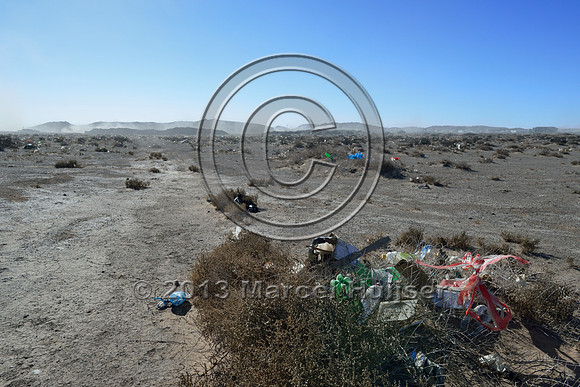 Garbage blown by the wind with the settlement of Tsagaan khad (White Rock) and coal dust clouds from the coal transfer station in the background, north of Gashuun-Sukhait, Gobi, Mongolia