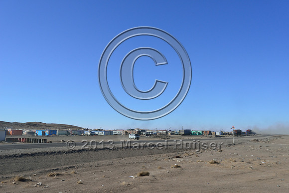 The settlement of Tsagaan khad (White Rock) and coal dust clouds from the coal transfer station in the background, north of Gashuun-Sukhait, Gobi, Mongolia