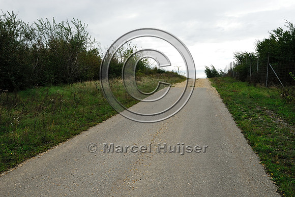 Low volume road (pavement transitions into gravel) on top of multifunctional overpass (wildlife and farm road, about 100 m wide), across A4 motorway, Parndorf, Austria