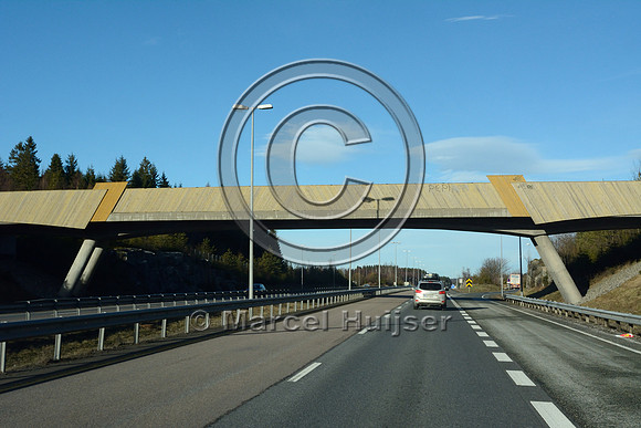 Bridge with a road and visual barriers across E6 motorway, near As, Norway